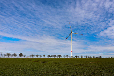 Wind turbines on field against sky