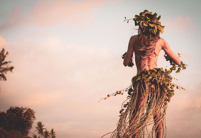 Low angle view of women standing on plant at sunset