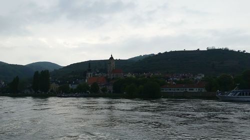 Houses by river in town against sky