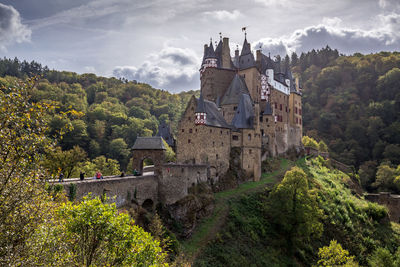 Castle by trees and buildings against sky