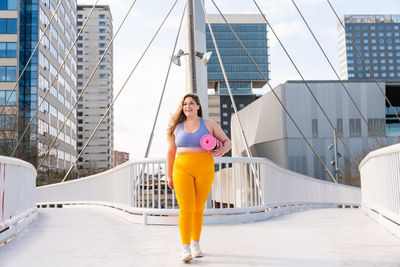 Full length of young woman walking on footbridge