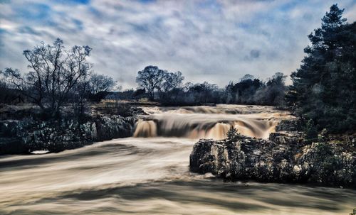 Scenic view of waterfall against sky