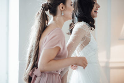 Side view of bridesmaid grooming bride