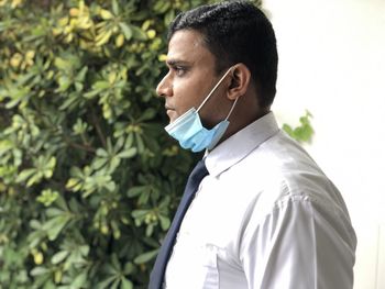 Portrait of young asian man with face mask standing outdoors