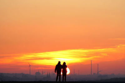 Silhouette man walking on field against sky during sunset