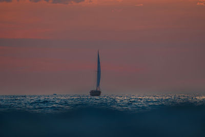 Sailboat sailing on sea against sky during sunset