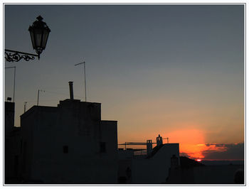 Silhouette buildings against sky at sunset