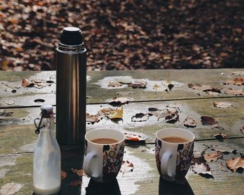High angle view of insulated drink container with coffee and milk on table