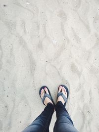 Low section of woman standing on sand at beach