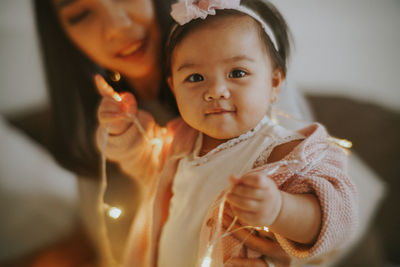 Smiling woman with daughter sitting on bed at home