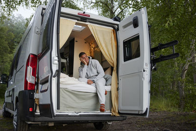 Man sitting in camper van in forest