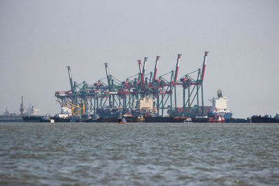 Cranes at commercial dock against clear sky