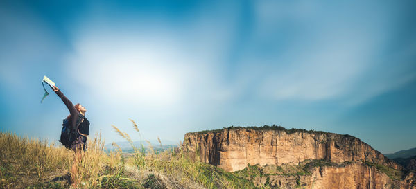 Rear view of man standing on mountain against sky