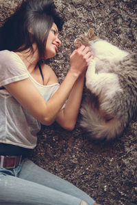 High angle view of woman lying with cat on floor