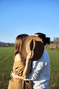 Rear view of woman standing on field against clear sky