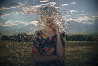 Water splashing on woman standing against sky