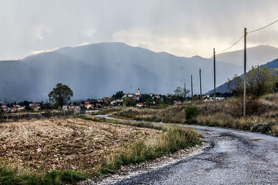 Road by mountains against sky