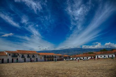 People on beach by buildings against blue sky