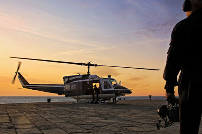 Helicopter aircrew against sea during sunset