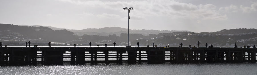 Silhouette pier on lake against sky