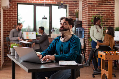 Portrait of smiling friends using laptop at office