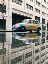 Blurred motion of taxi on street against buildings in city