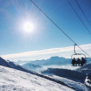 Ski lift over snow covered mountains against sky