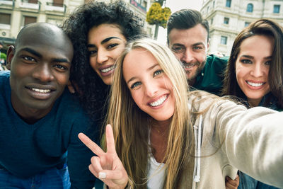 Portrait of cheerful friends bending in city