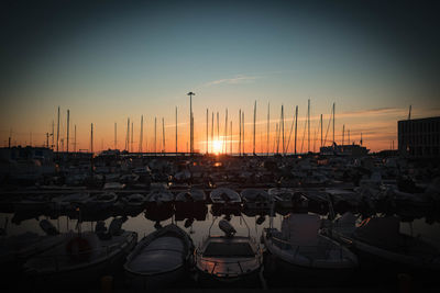 Boats moored at harbor during sunset