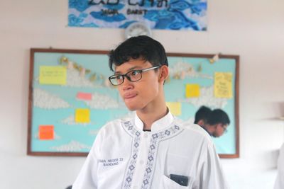 Boy standing against blackboard in classroom