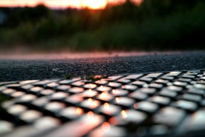 Footpath by empty road at sunset