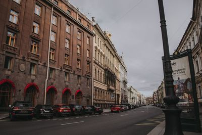 Traffic on road by buildings in city against sky