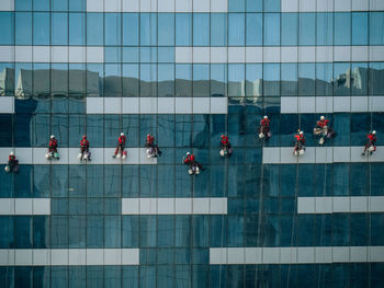 Workers cleaning window of office building