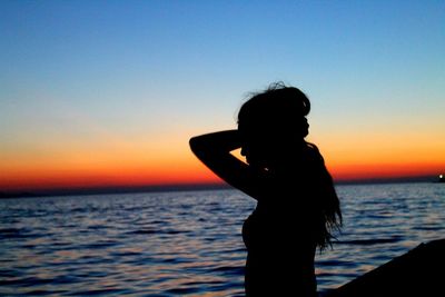 Silhouette woman at beach against sky during sunset