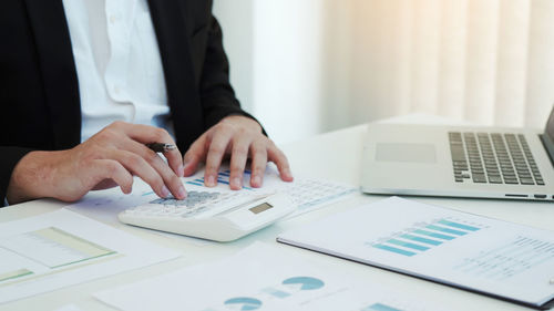 Midsection of man using laptop on table