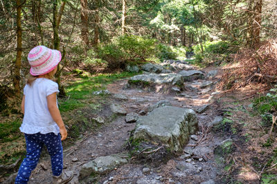Full length of girl walking on rock in forest