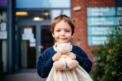 Cute primary school pupil holding teddy bear