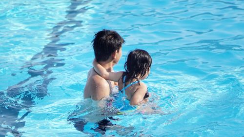 High angle view of father and daughter in swimming pool