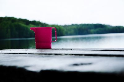 Close-up of red container against built structure in lake