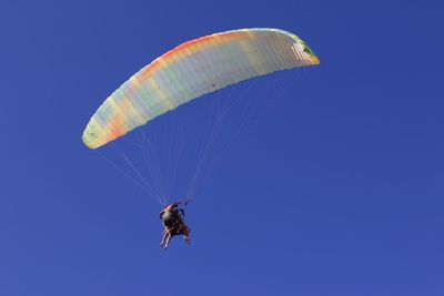 Low angle view of person paragliding against clear blue sky