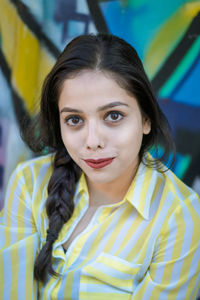 Portrait of smiling young woman against graffiti wall