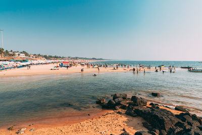 People at beach against clear sky