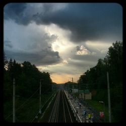 Train moving on railroad track against cloudy sky