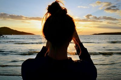 Rear view of woman at beach during sunset