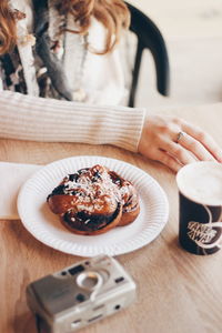 Midsection of woman having food and drink in cafe