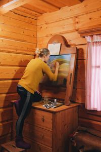 Rear view of woman drawing on canvas in cottage