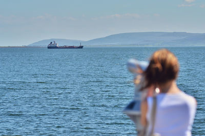 Woman in sea against sky