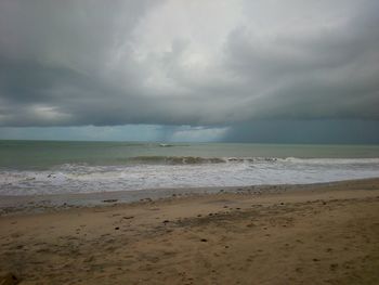 Scenic view of beach against cloudy sky