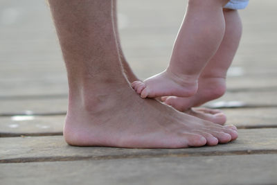 Newborn child standing on father's feet