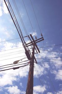 Low angle view of electricity pylon against blue sky